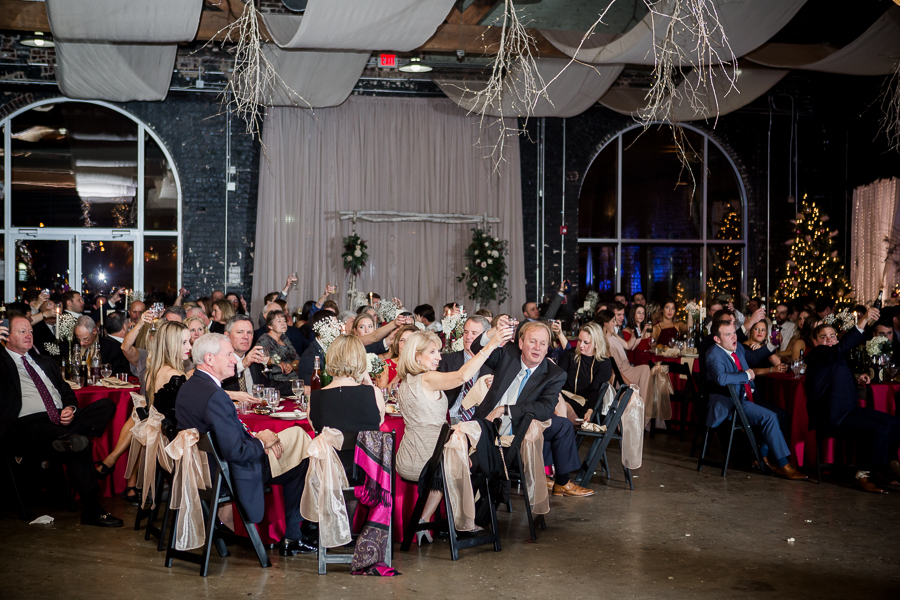 All the guests raise their glasses during the toasts during the reception pictures at this winter wedding at Knoxville Wedding Venue, Jackson Terminal, by Knoxville Wedding Photographer, Amanda May Photos.