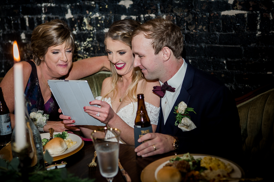 Bride and groom and mother of the bride look at the same day slideshow during the reception pictures at this winter wedding at Knoxville Wedding Venue, Jackson Terminal, by Knoxville Wedding Photographer, Amanda May Photos.