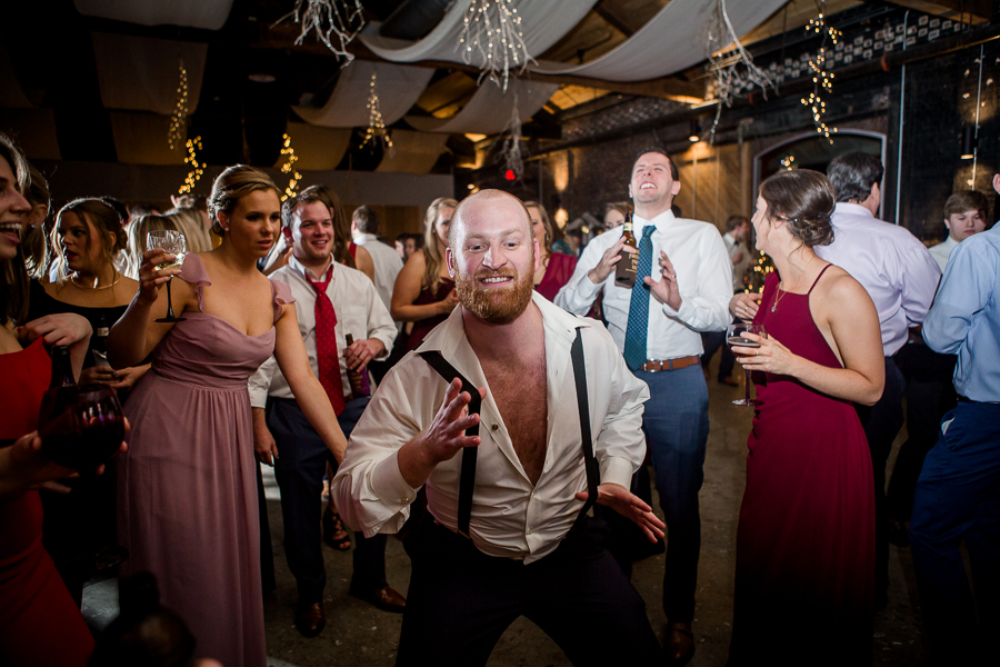Holding onto his suspenders during the dancing reception pictures at this winter wedding at Knoxville Wedding Venue, Jackson Terminal, by Knoxville Wedding Photographer, Amanda May Photos.