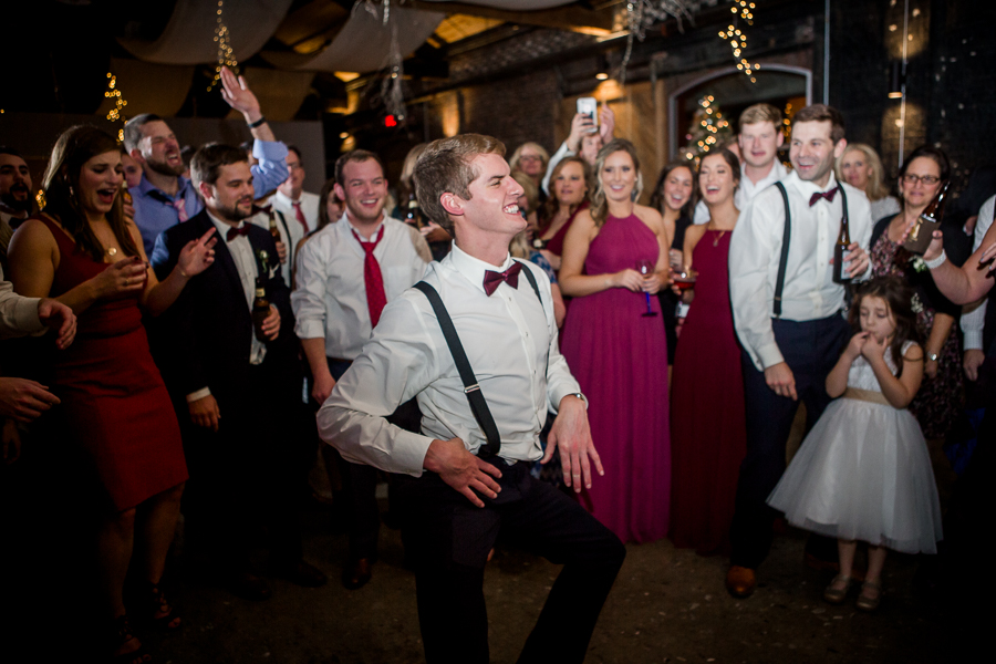 Brother of the bride dancing in the middle of the circle during the dancing reception pictures at this winter wedding at Knoxville Wedding Venue, Jackson Terminal, by Knoxville Wedding Photographer, Amanda May Photos.