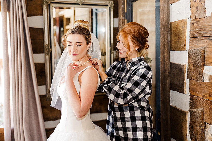 bridesmaid putting on pearls at this strawberry creek wedding