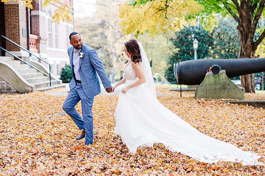couple walking through leaves at this urban elopement