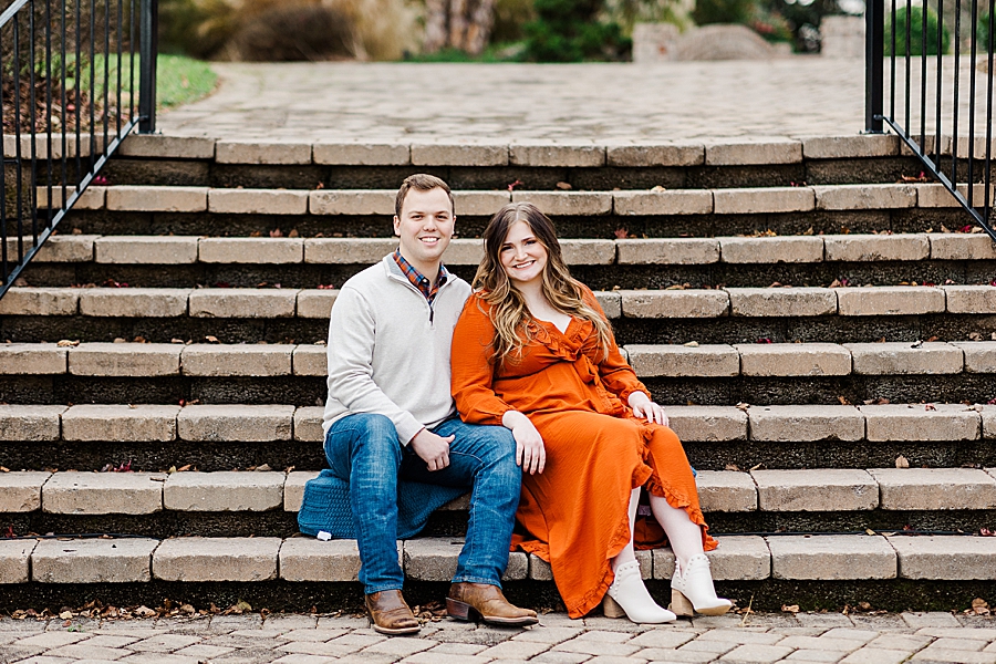 couple sitting on steps at winter engagement