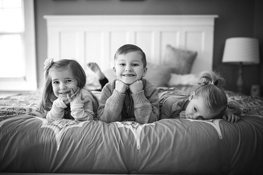 Laying on their tummies on the bed at this lifestyle family session by Knoxville Wedding Photographer, Amanda May Photos.