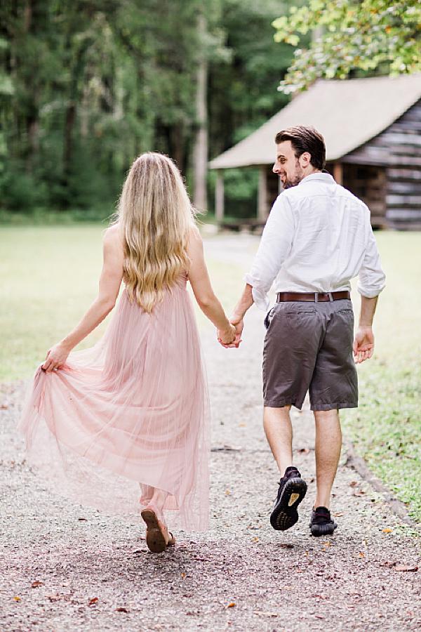 walking towards a cabin at cades cove engagement session