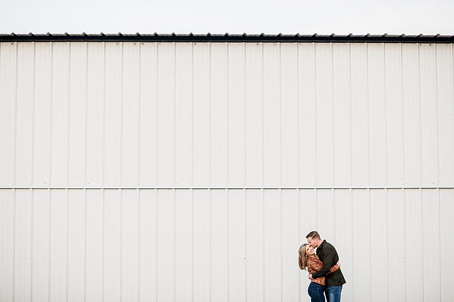 couple kissing in front of an airplane hanger at island home airport