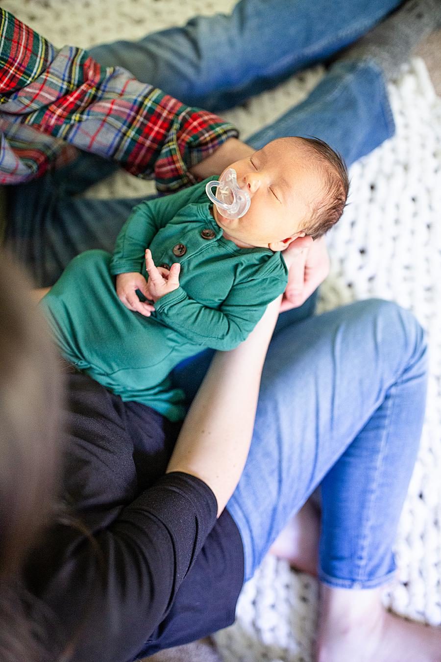 newborn dressed in green with a pacifier
