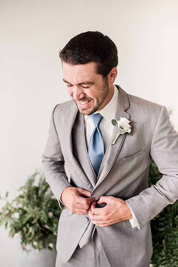 groom buttoning jacket at the press room
