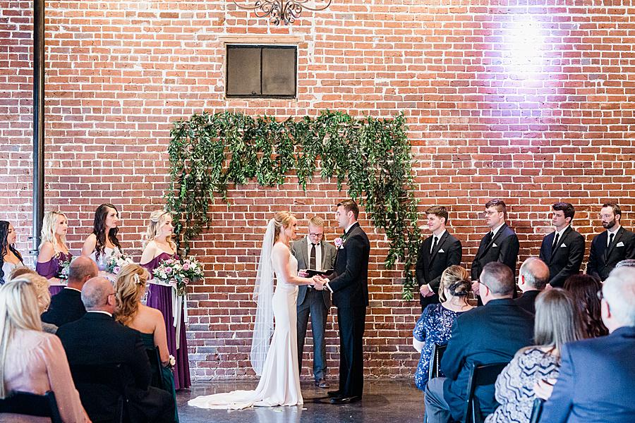 exchanging vows in front of a greenery backdrop