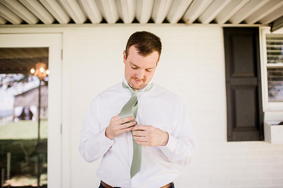 groom tying mint green tie