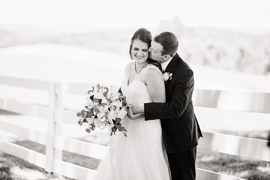 groom kissing bride in black and white at the white rose