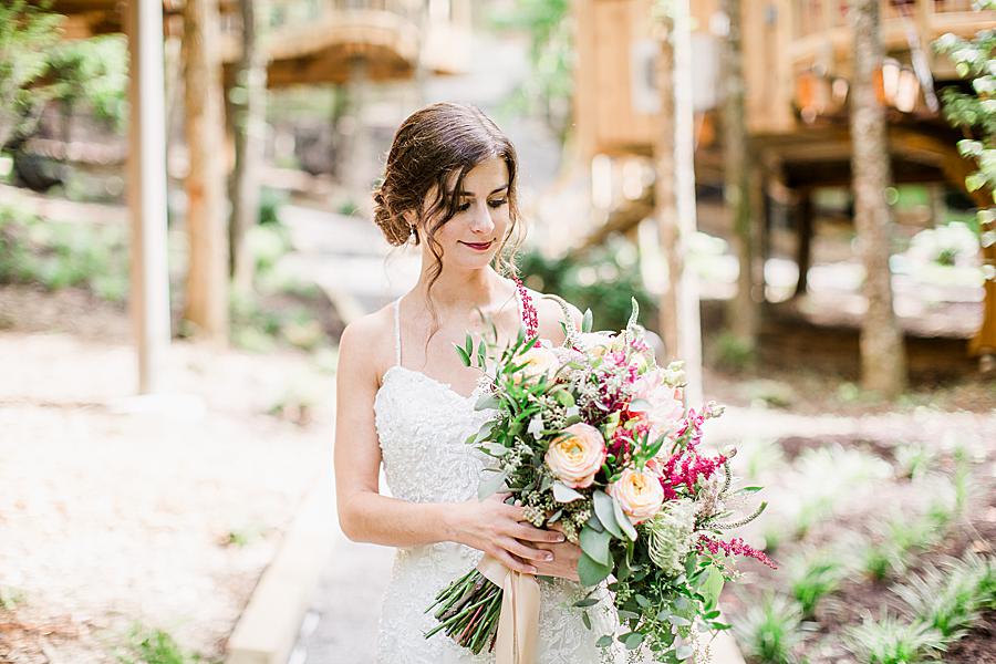 bride looking at bouquet at treehouse grove styled shoot