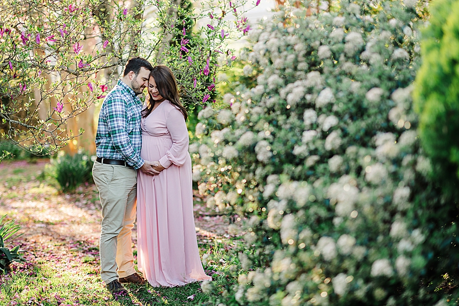 standing by white blooms at ut gardens maternity session