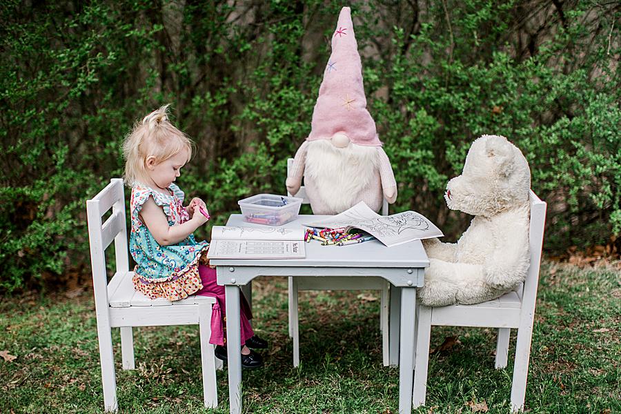 2 years old sitting at table with teddy and gnome