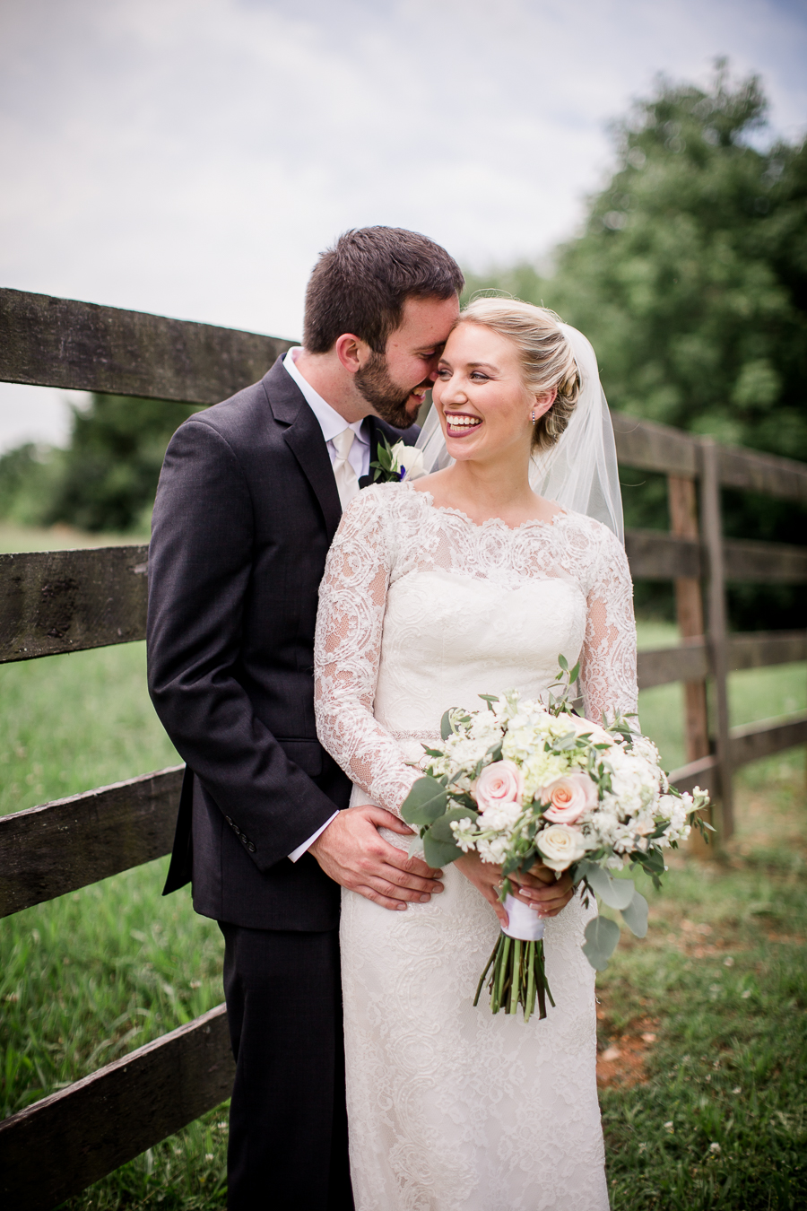 He whispers in her ear against the fence at these 2017 favorite weddings by Knoxville Wedding Photographer, Amanda May Photos.