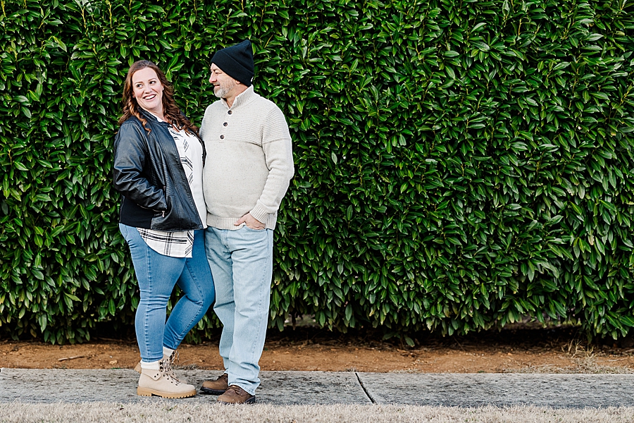 couple in front of dark green hedge