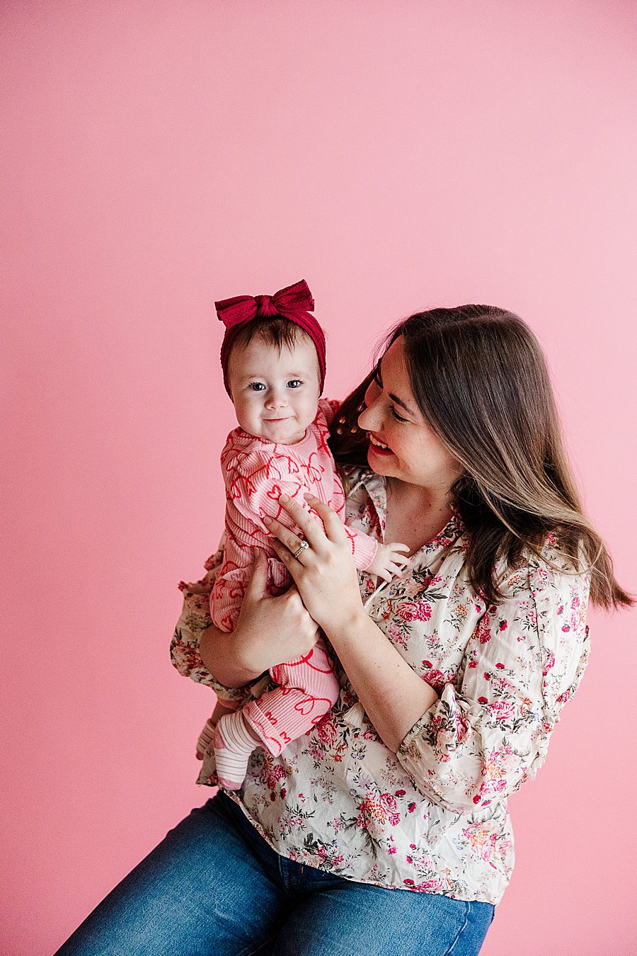 mom and daughter in front of pink backdrop