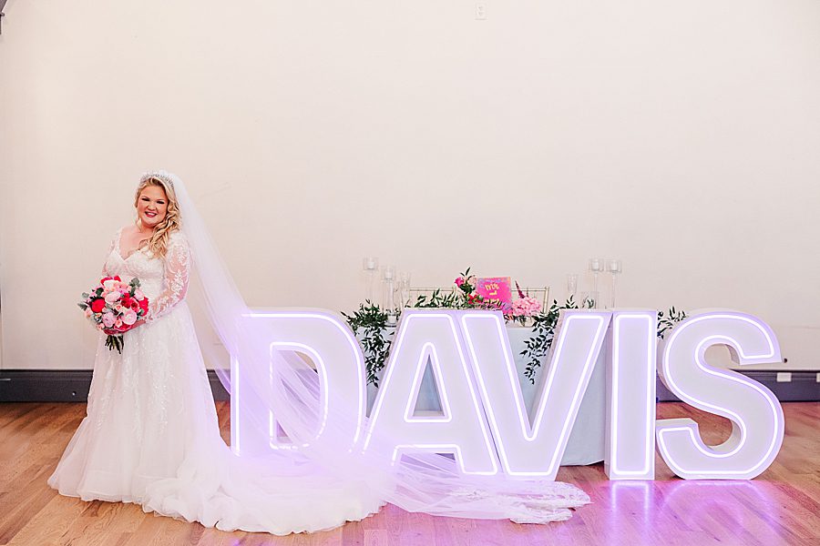 bride and groom by marquee letters at the brookside