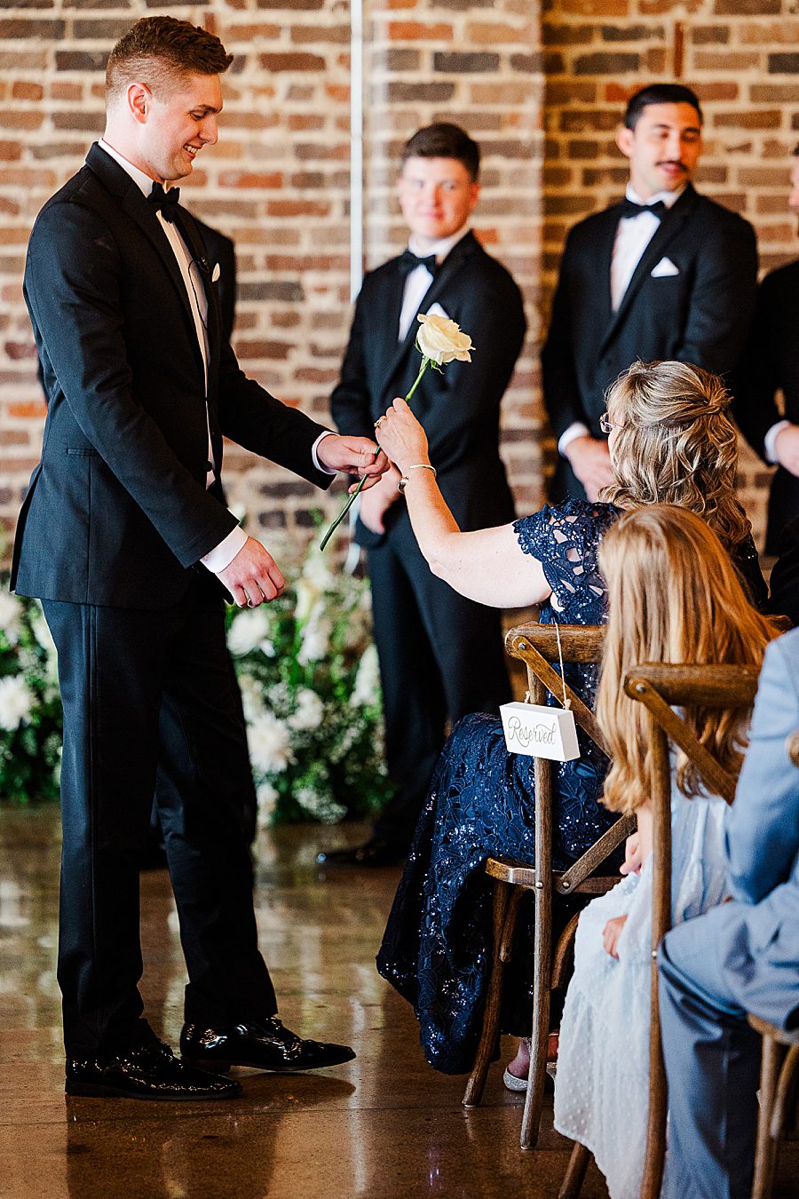 groom giving mom flower at summer press room wedding