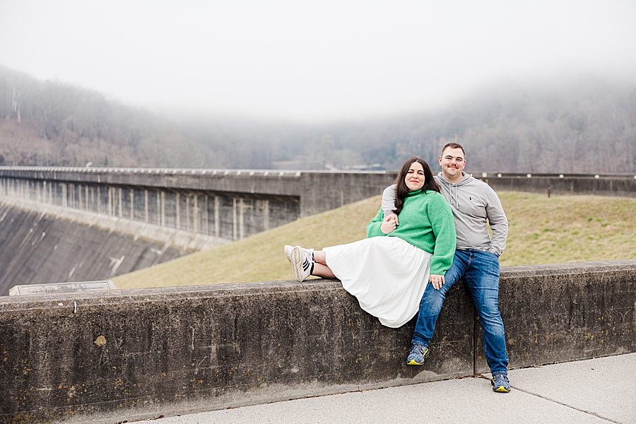 couple sitting in front of dam at norris dam engagement