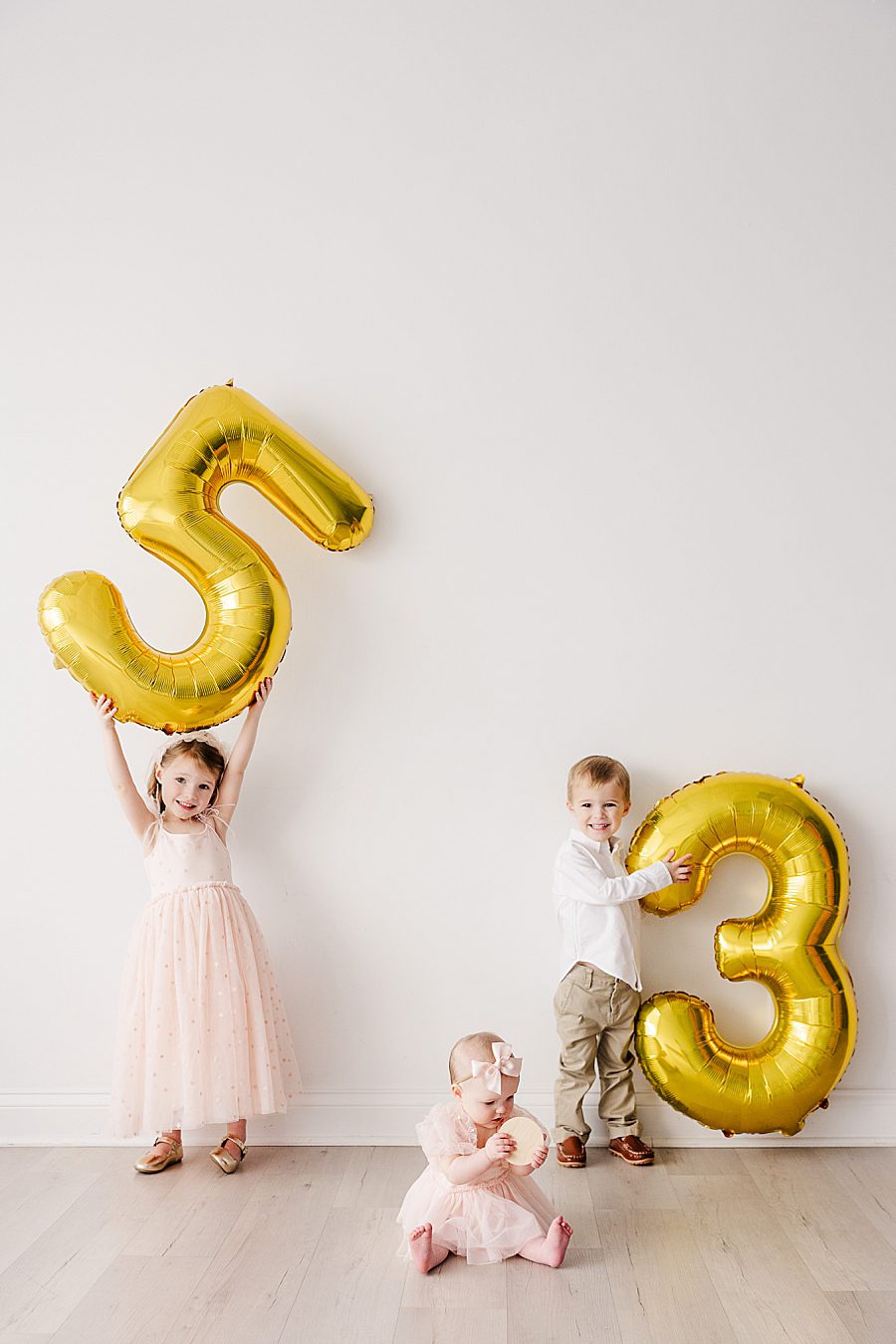 kids holding balloons at white room 6 month session