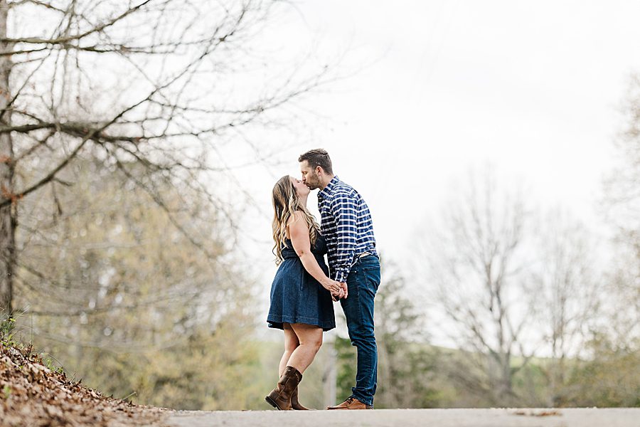 couple kissing at engagement session with a horse
