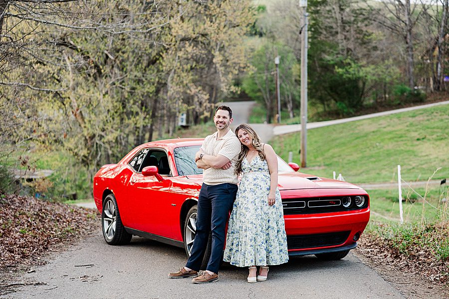 couple in front of red sports car at engagement session with a horse