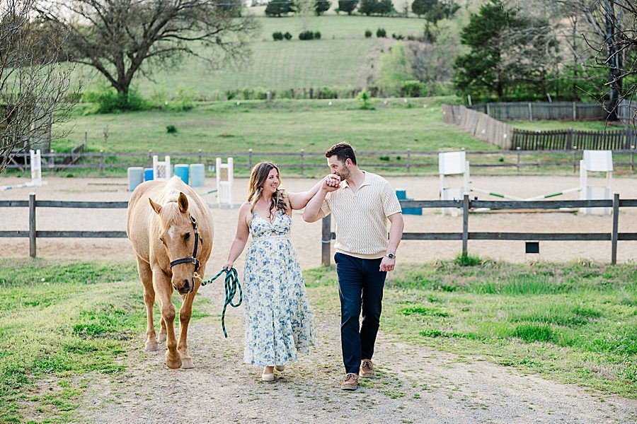couple walking on farm with a horse