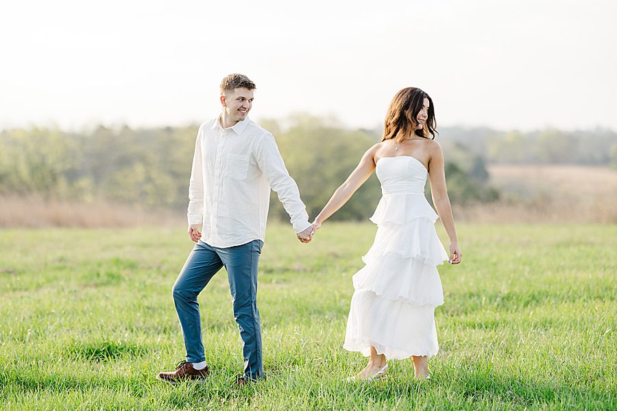 couple holding hands in field at sunrise marblegate farm engagement