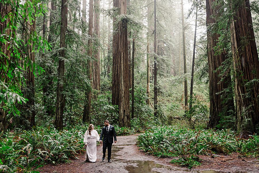 bride and groom walking down rainy path