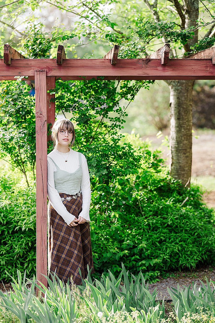 girl leaning against red arbor at ut gardens senior session