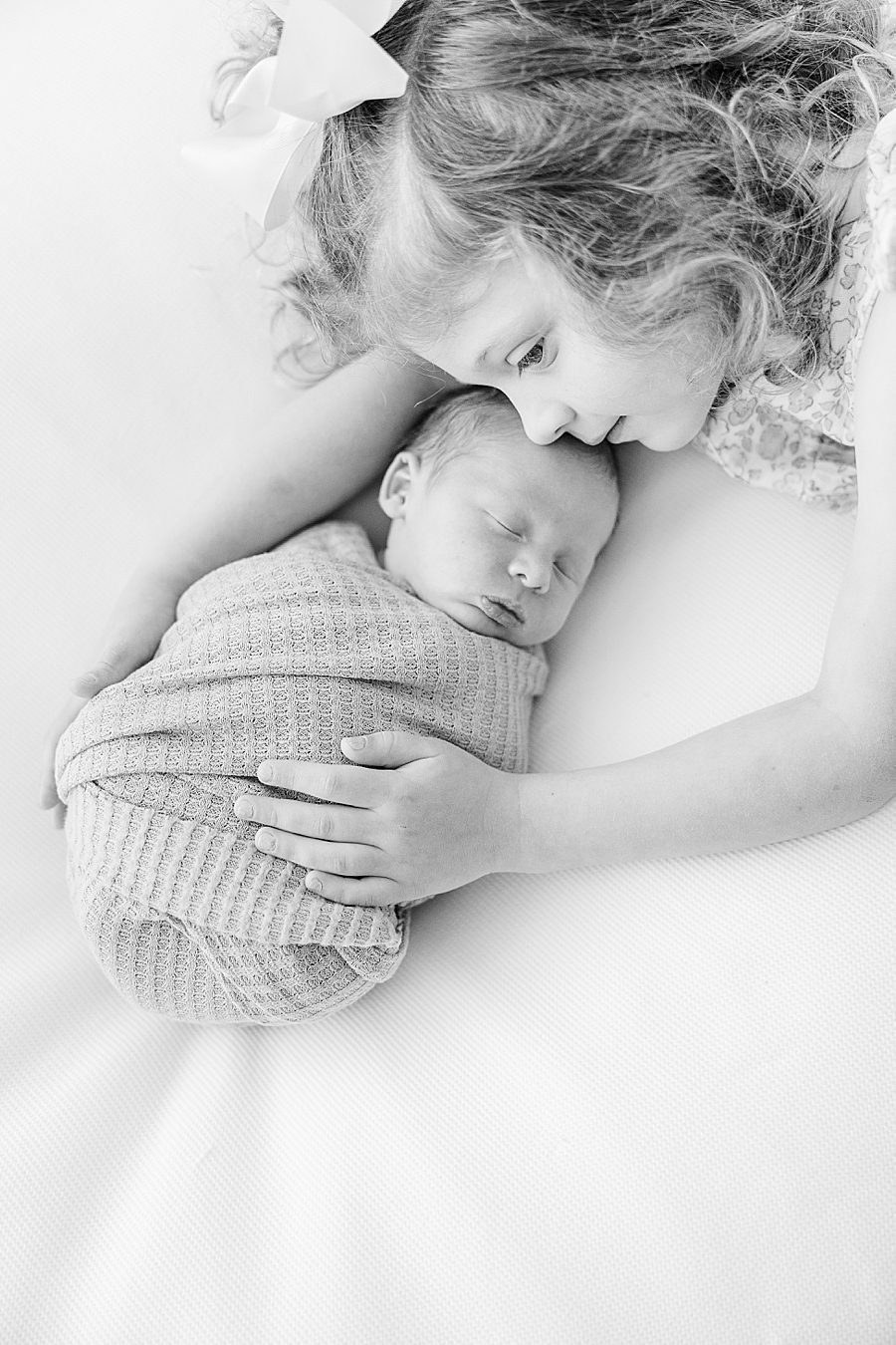 black and white photo of siblings at white room studio newborn session