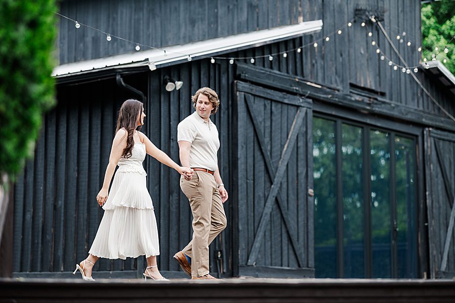 couple walking in front of barn at castleton estate engagement
