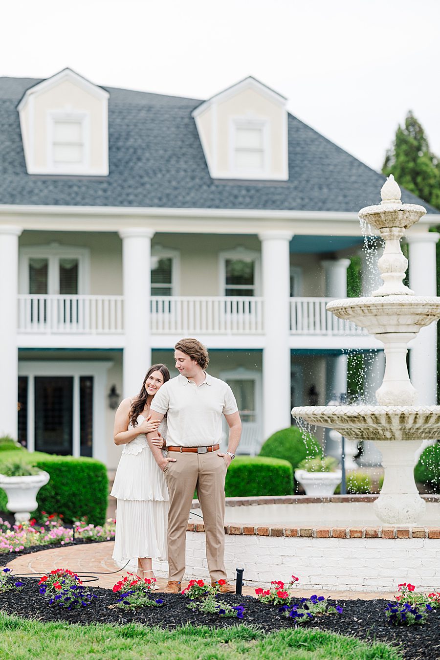 couple standing in front of manor at castleton estate engagement