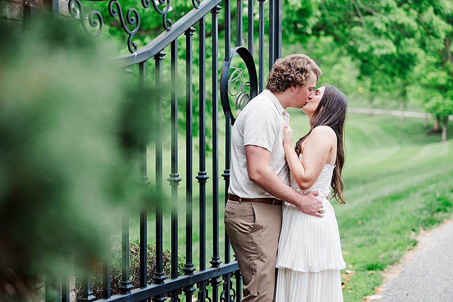 couple kissing in front of black gate