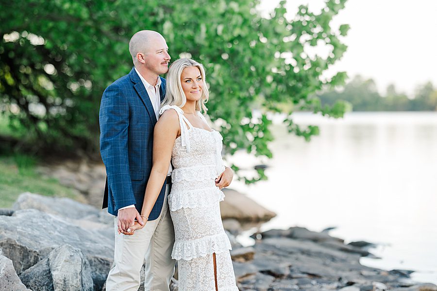 couple standing on rocks staring at water