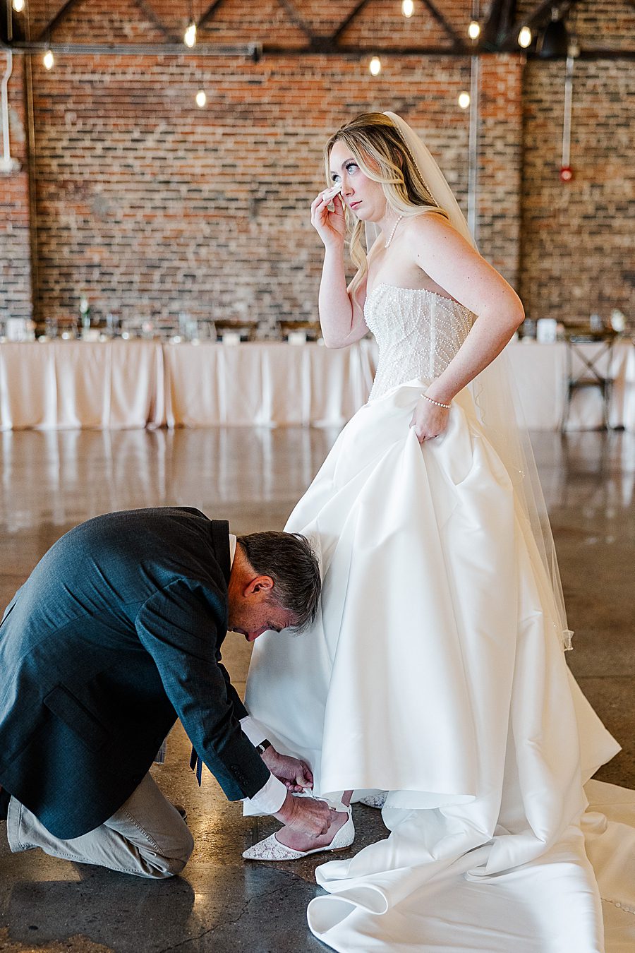 dad helping bride with shoes at press room catholic wedding