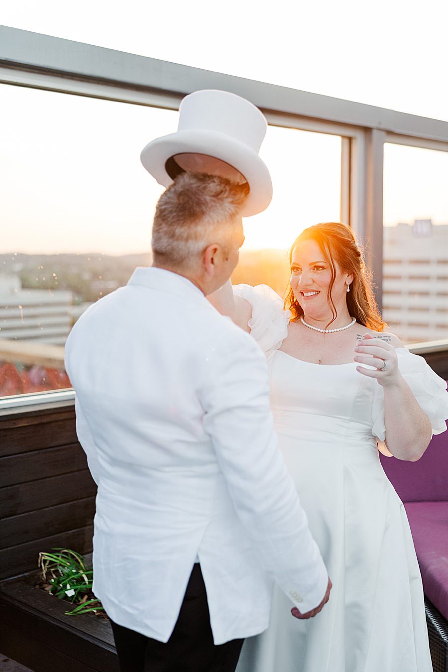 bride putting on groom's white top hat