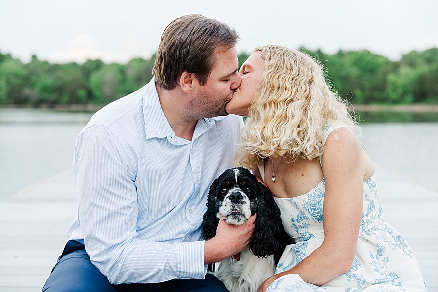 couple kissing on dock with dog between them