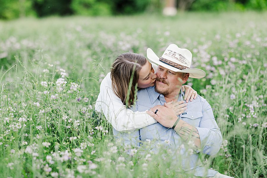 kiss on cheek while sitting in wildflower field at mead's quarry anniversary