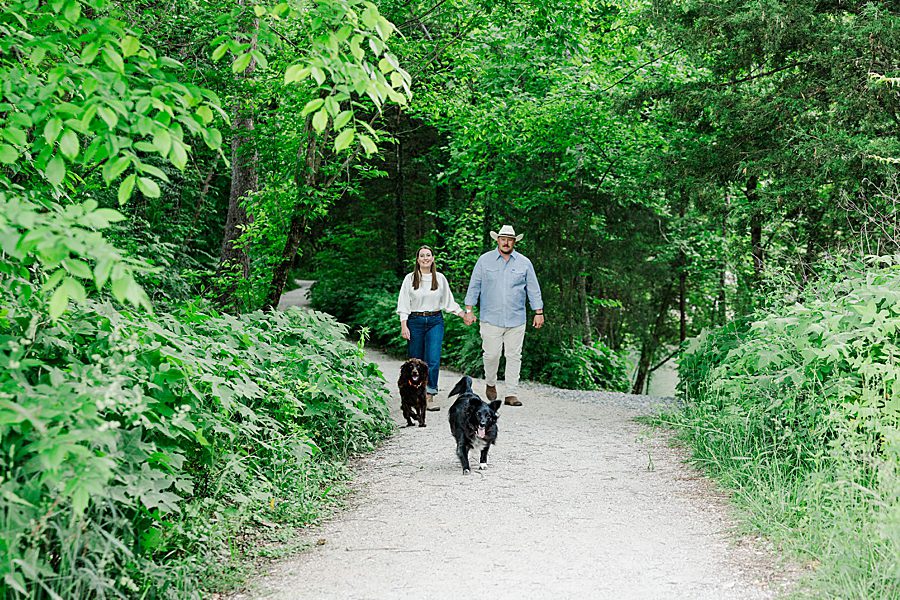 couple walking dogs down gravel path