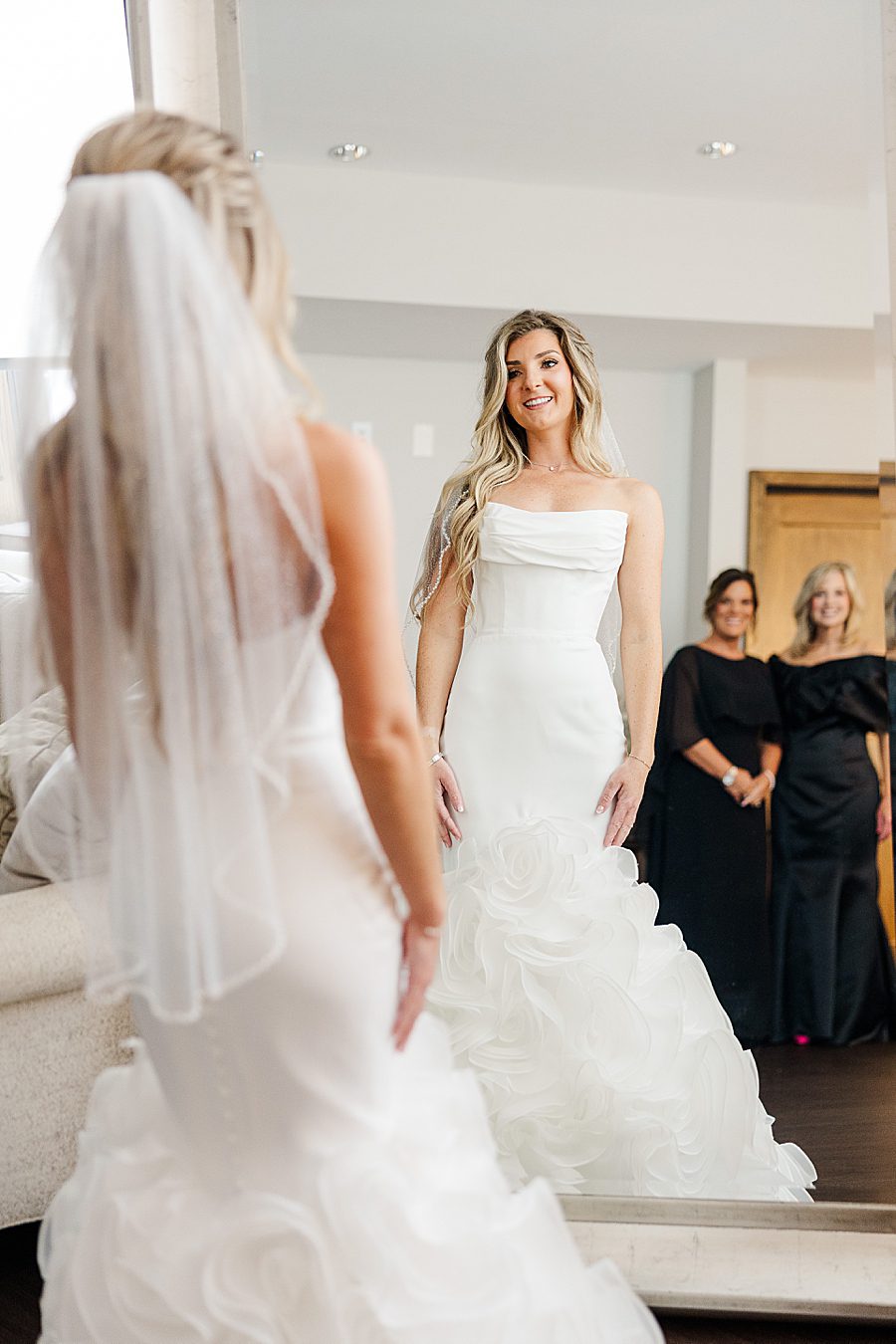 bride looking in mirror before summer press room wedding