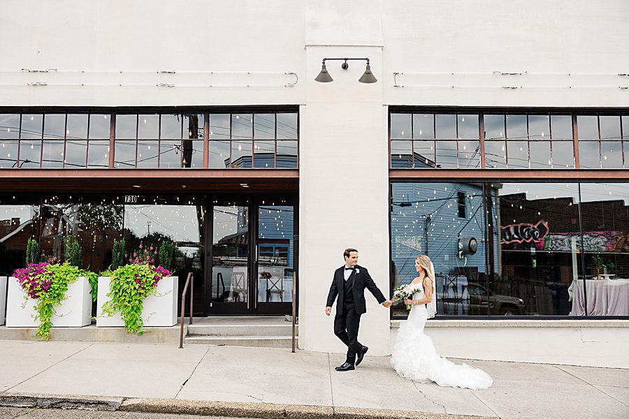 bride and groom holding hands at summer press room wedding