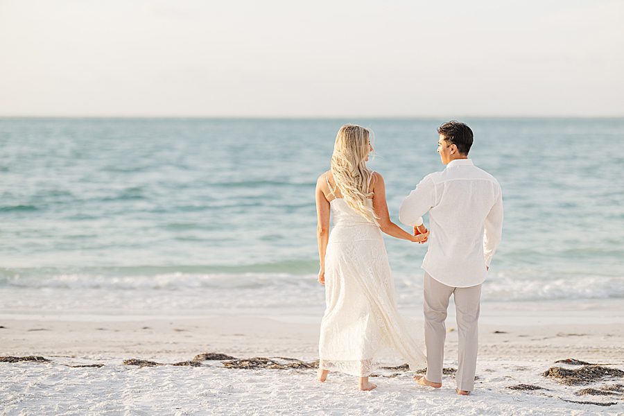 couple walking along beach at anna maria island anniversary session
