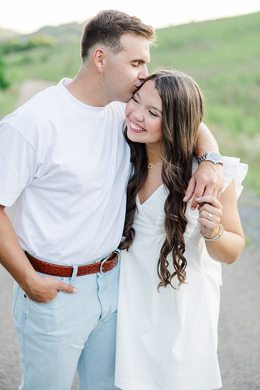 man kissing woman on temple