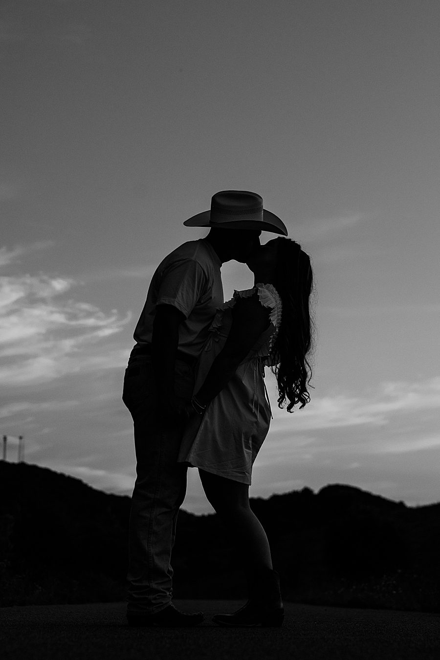 black and white photo of couple kissing at sunset