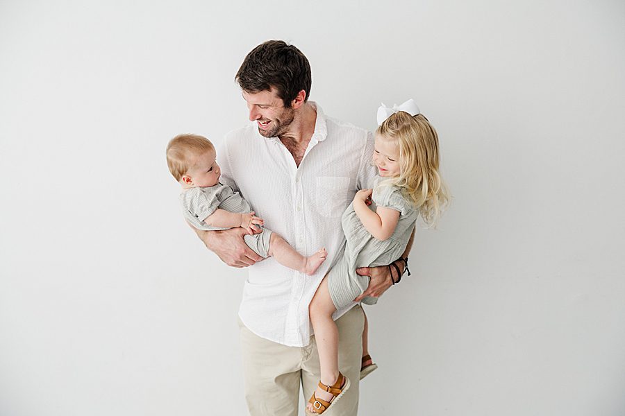 dad holding kids at white room family session