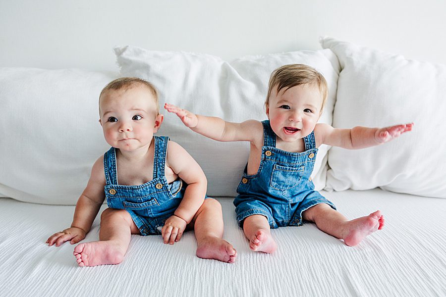 babies sitting on white bed at nine month twins milestone session