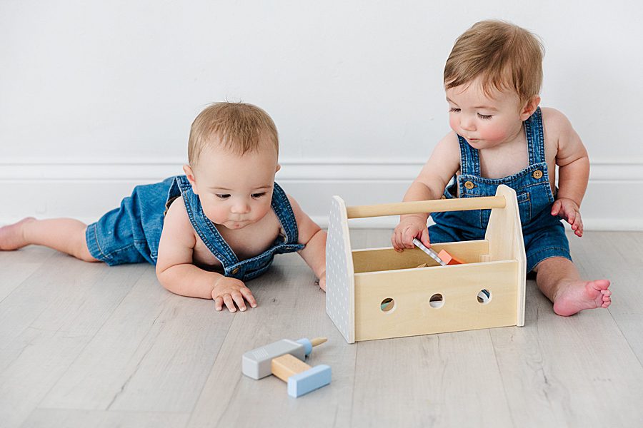 boys playing with wooden toolbox at nine month twins milestone session