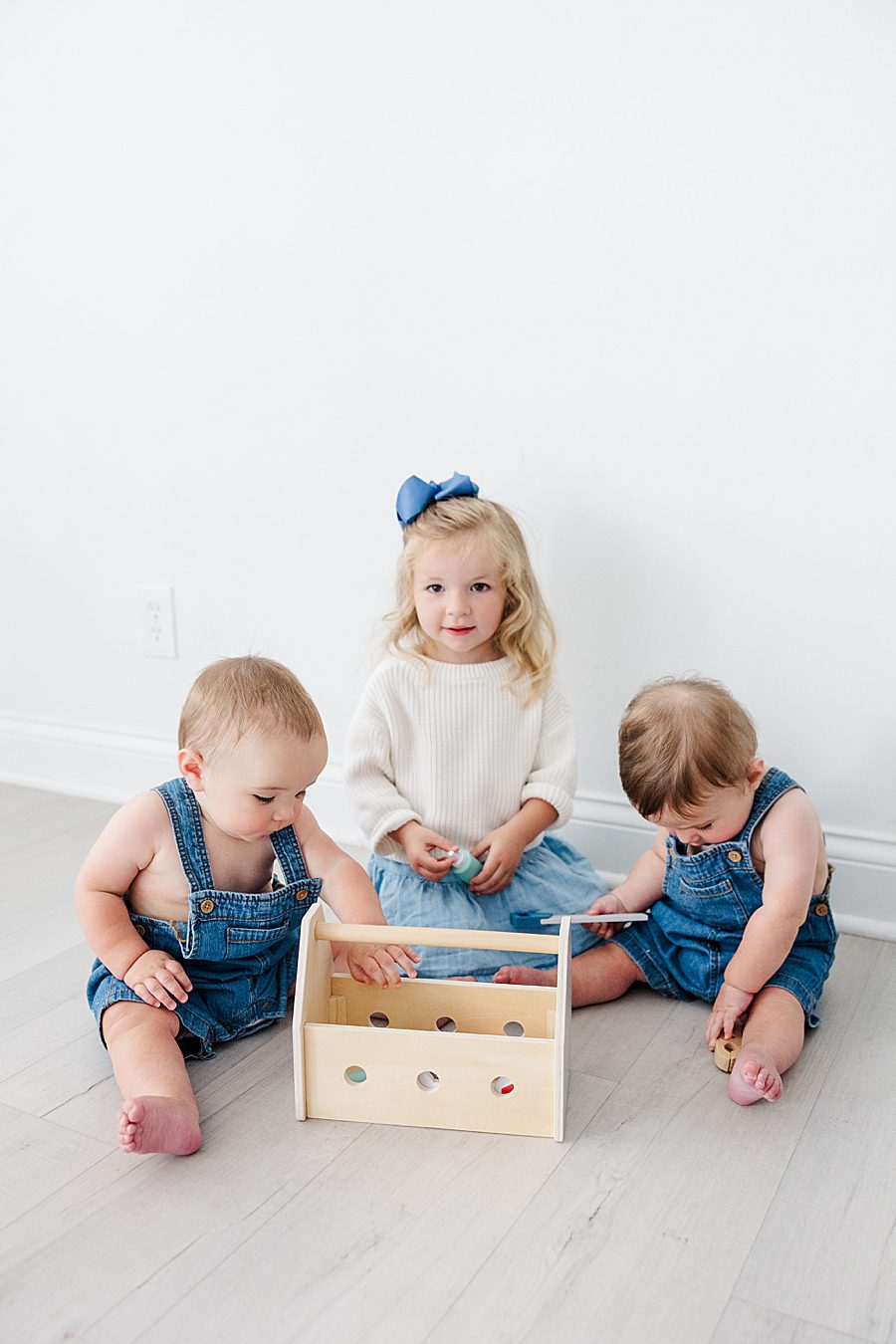 siblings playing with wooden tool box during photo session